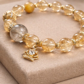 Golden rutilated quartz and citrine bracelet with crown charm, featuring natural crystal beads and gold accents for wealth and confidence
