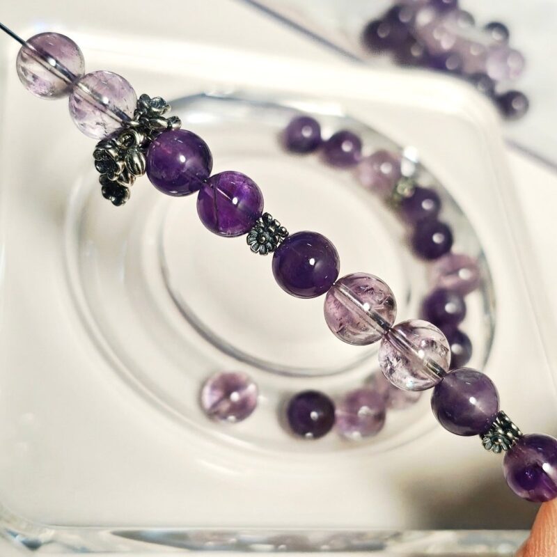 Hand-stringing the amethyst crystal bracelet on elastic cord, with Thai silver spacers and sakura bead cap