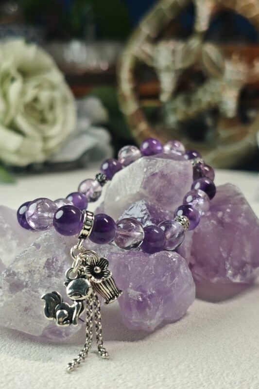 Violet Hour amethyst bracelet styled beside white and blue roses on raw amethyst crystals.