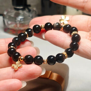 Close-up detail of silver obsidian beads and clover charm