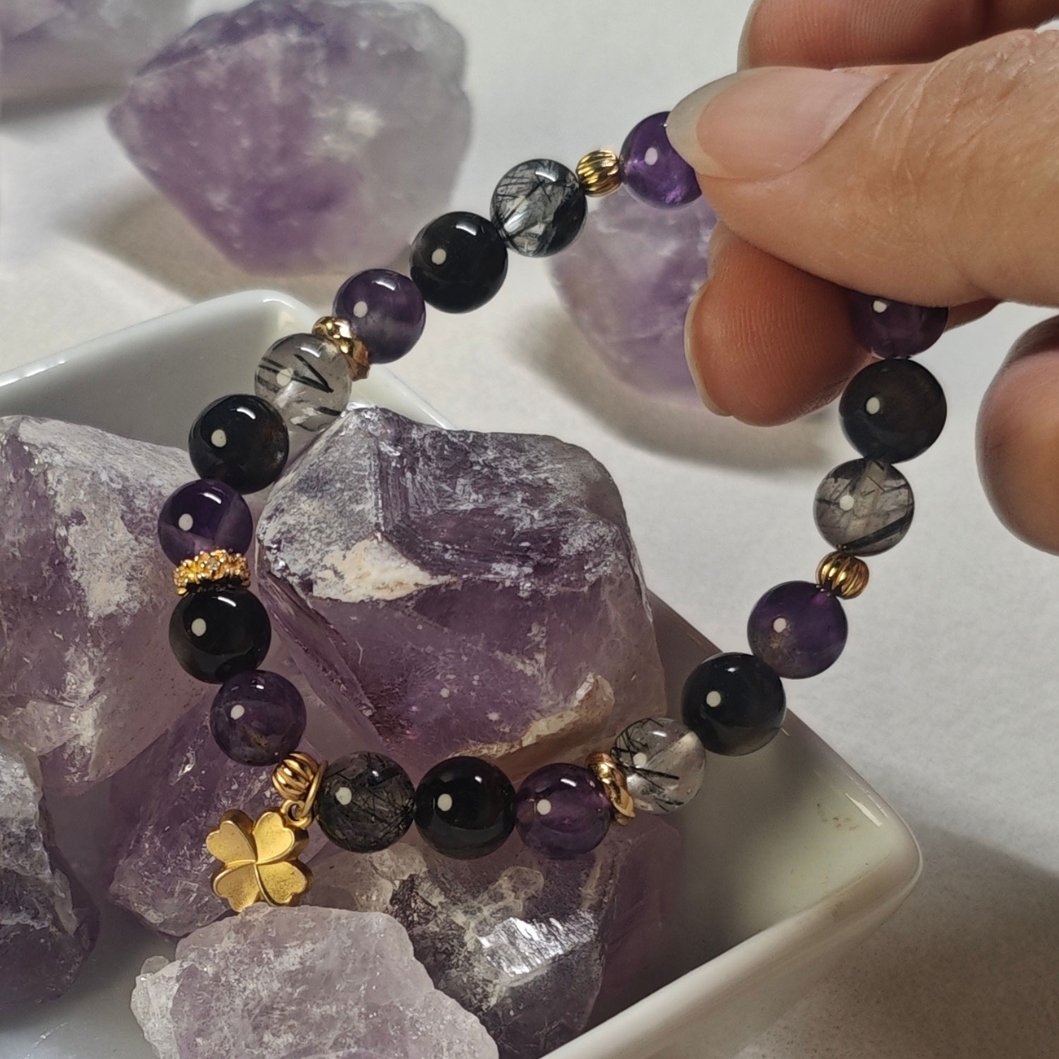 Angled view highlighting the amethyst, silver obsidian, black rutilated quartz, and four-leaf clover charm
