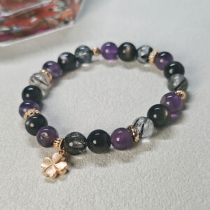 Close-up detail of the Four-Leaf Clover Protection Bracelet showing polished gemstone beads and the four-leaf clover charm