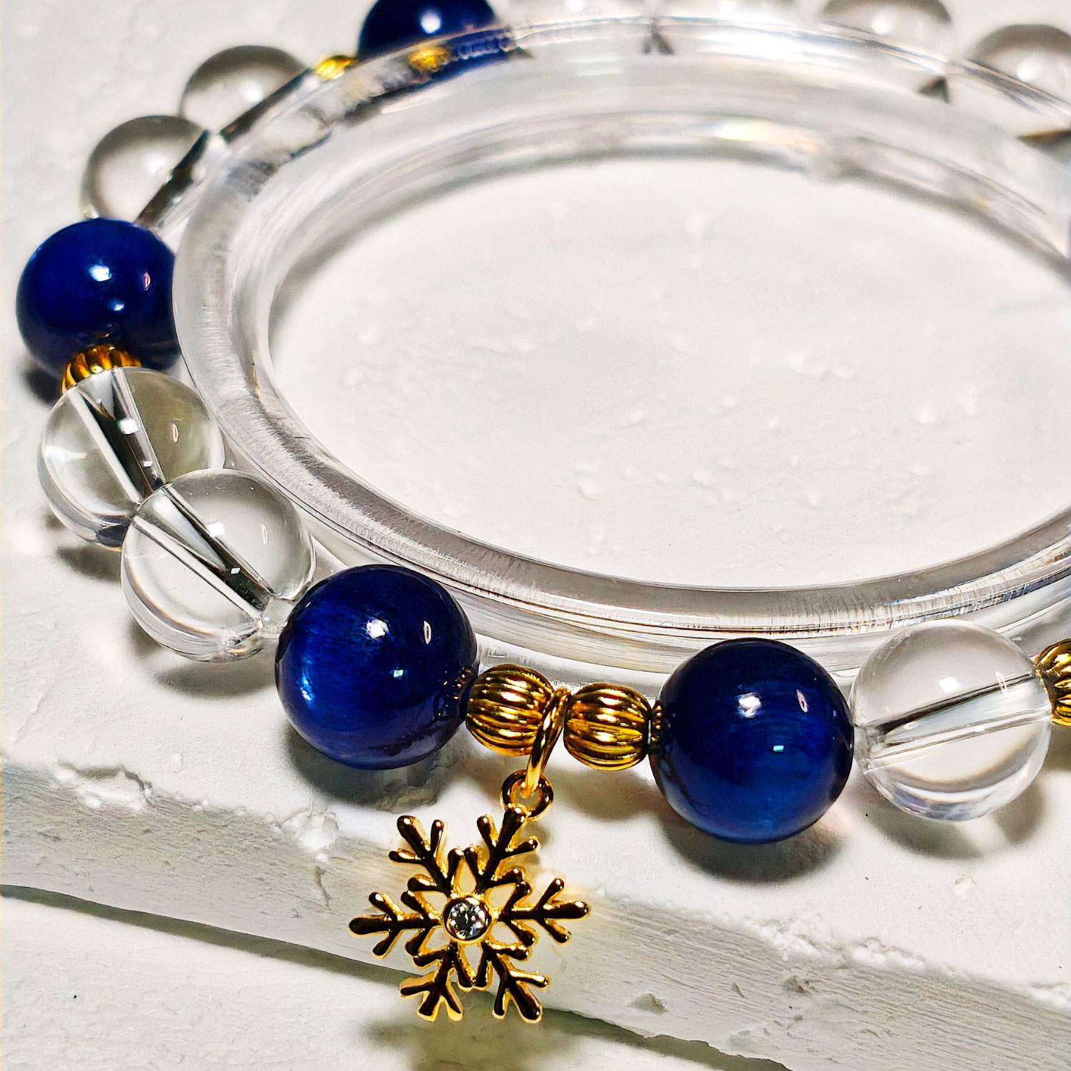 Detailed view of the gold-plated 925 sterling silver snowflake charm and natural crystal beads on SnowPoise CL
