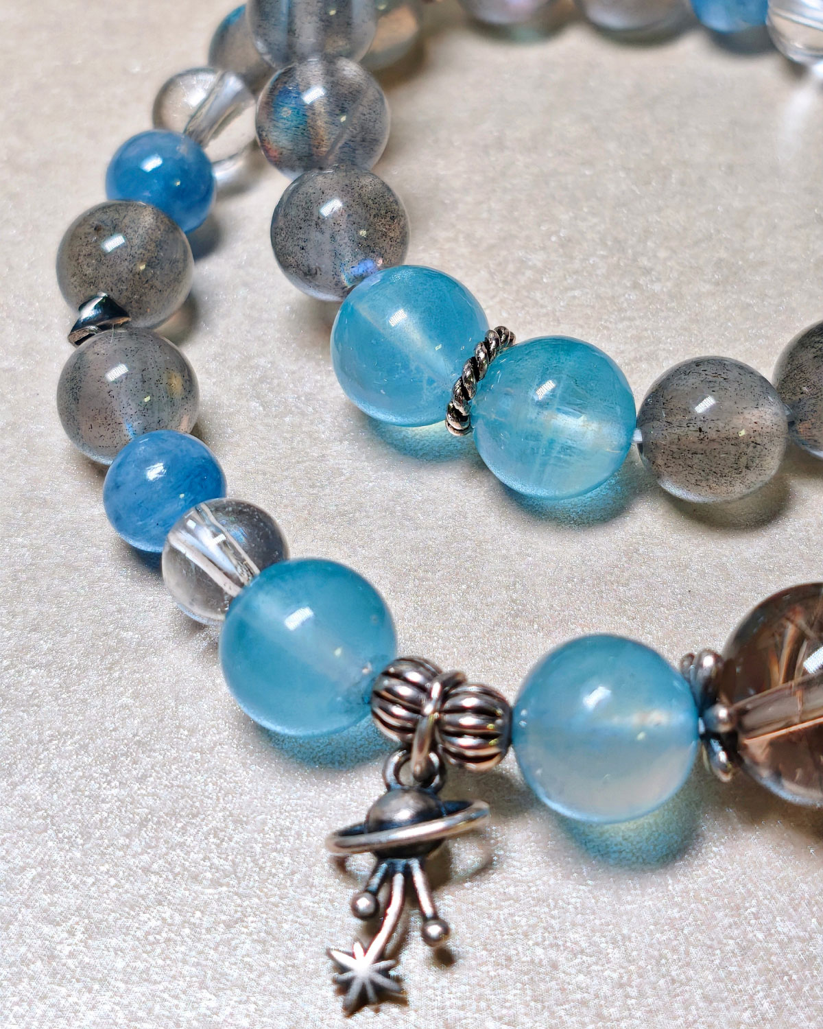 Close-up detail of the planet charm and crystals on the StellarEase CL bracelet