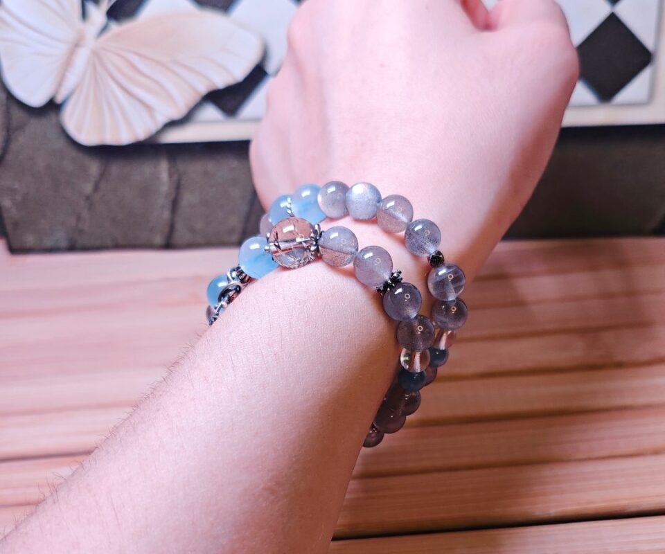 The Career Orbit crystal bracelet worn double-wrapped on a wrist, with blue aquamarine beads and a silver planet charm.