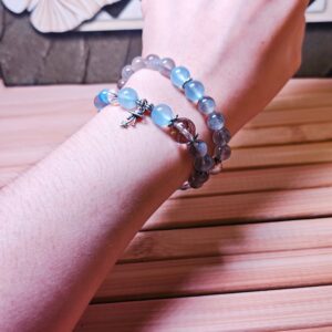 The Career Orbit crystal bracelet worn wrapped twice around a wrist, showing its blue aquamarine and kyanite beads and a small silver planet charm.
