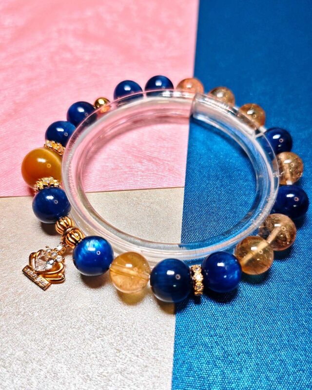 Bracelet laid flat on pink and blue silk, gold tiger's eye and pale citrine beside deep blue kyanite