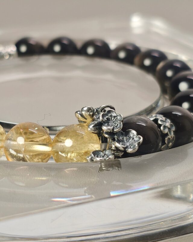 Close view of the equinox crystal bracelet where silver obsidian meets ice citrine, with a sakura bead cap in sterling silver