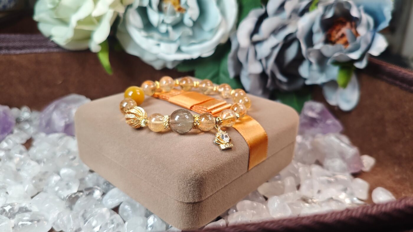 Golden rutilated quartz and citrine bracelet resting on its gift box with an orange ribbon, ready to give.
