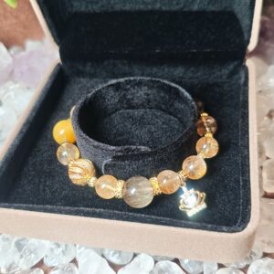 Golden rutilated quartz and citrine bracelet resting in its gift box.