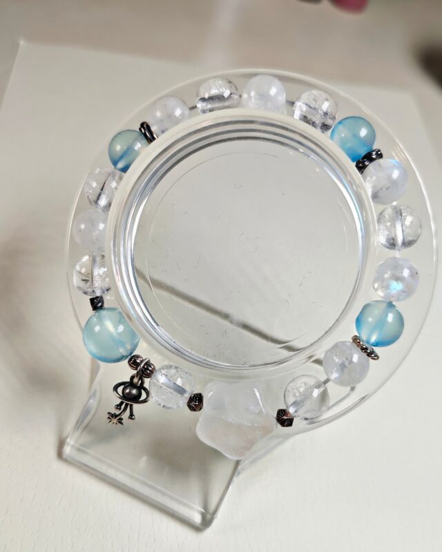 Bracelet circled around a clear ring stand seen from above, moonstone aquamarine and clear quartz beads in view