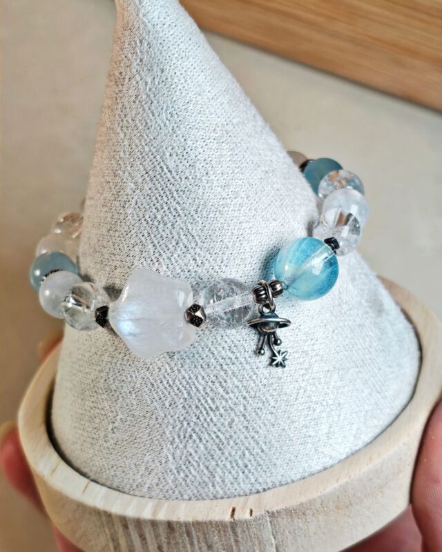 Bracelet wrapped around a white paper cone, the s925 sterling silver planet charm and its star hanging at the side