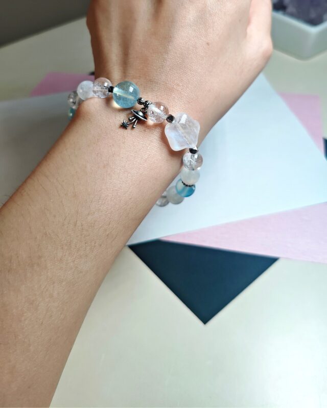Blue moonstone aquamarine clear quartz bracelet worn on the wrist, the planet charm resting at the side