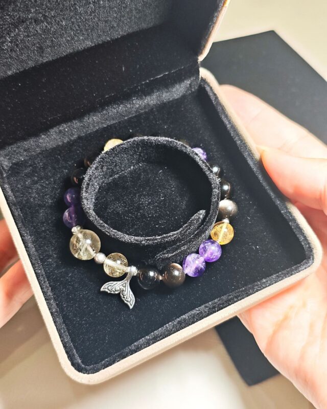Rising Current crystal bracelet resting inside its black velvet gift box, held open in two hands.