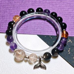 Mermaid tail crystal bracelet on a clear display stand, with silver obsidian, golden rutilated quartz, Ice Citrine and amethyst beads.