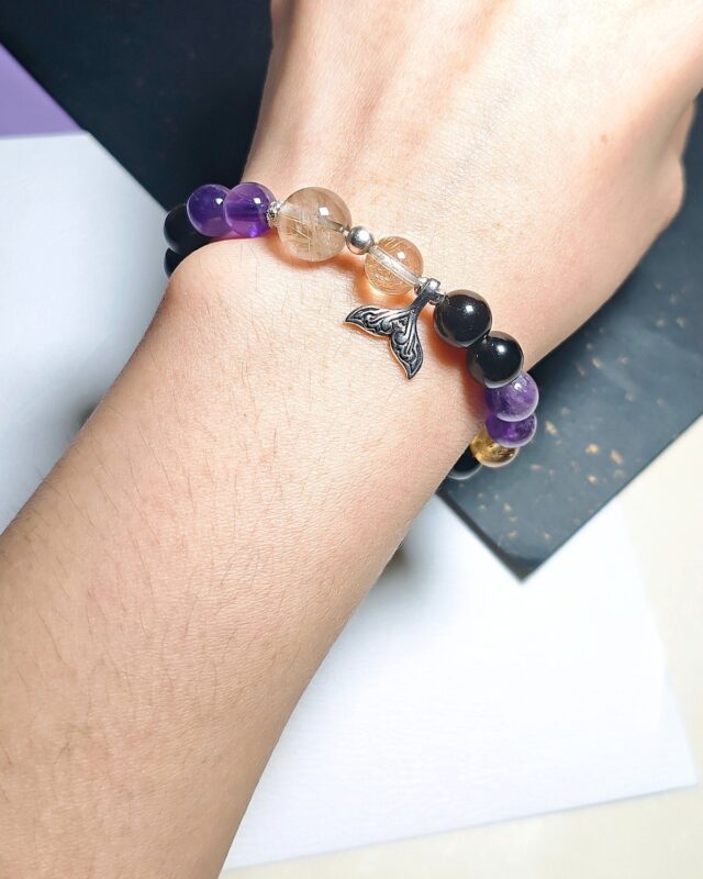 Rising Current crystal bracelet worn on a wrist, with the mermaid tail charm sitting at the front.