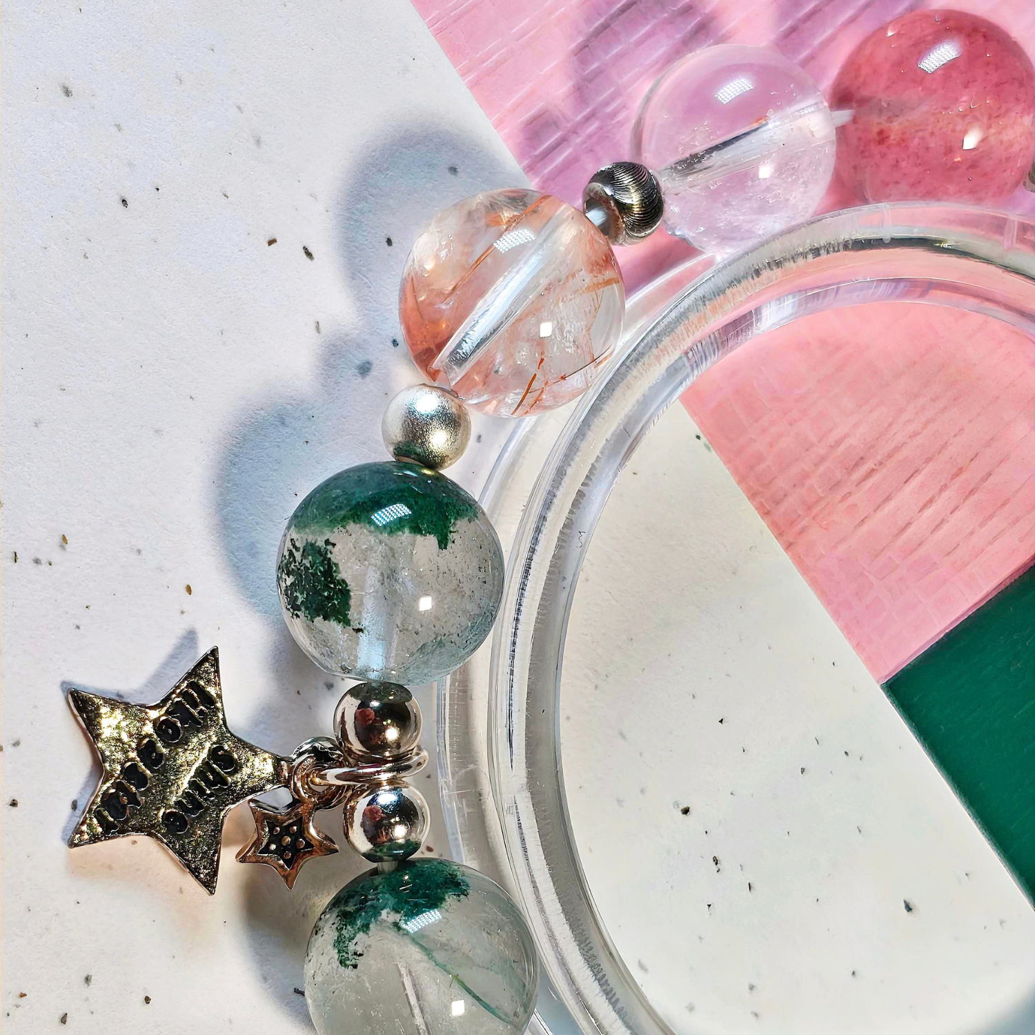 Close view of the black gold super seven bracelet, showing its green phantom quartz beads and sterling silver star charm.