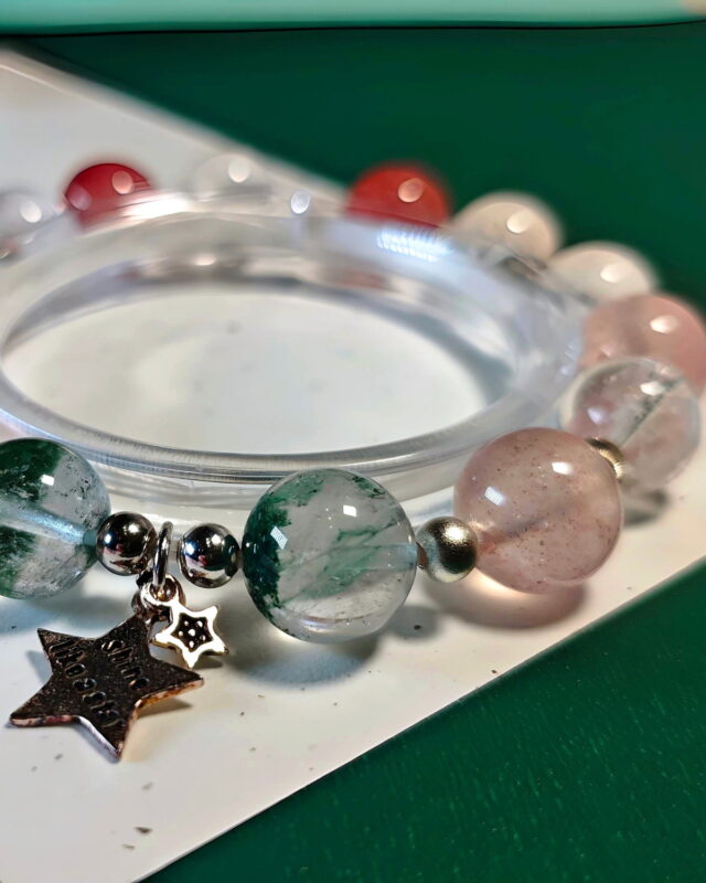 Close view of the Rooted Glow crystal bracelet, with its sterling silver star charm beside the green phantom quartz beads.