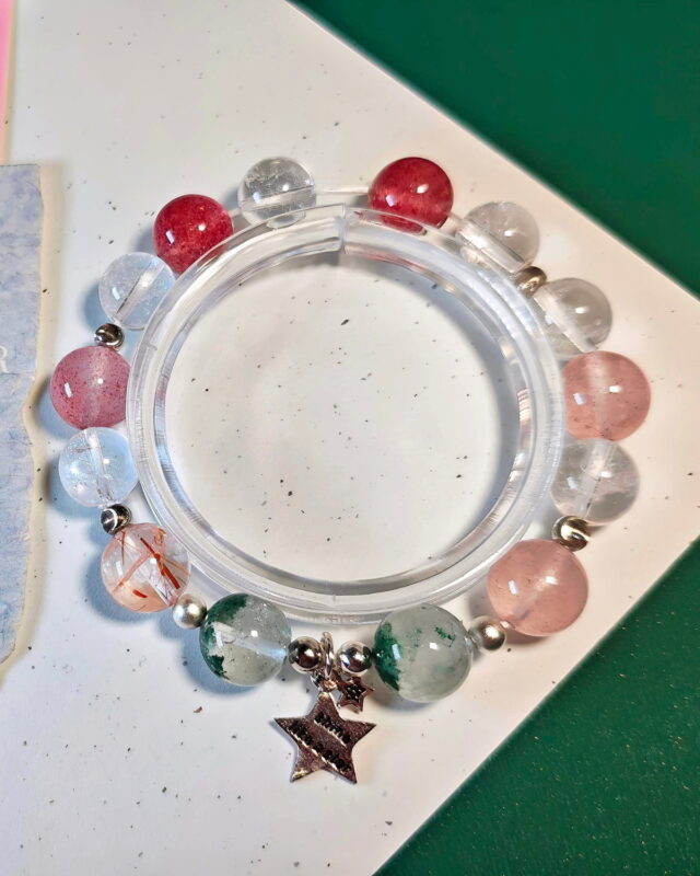 Black gold super seven bracelet laid full circle, showing the ice strawberry quartz, ice clear quartz and green phantom quartz beads.