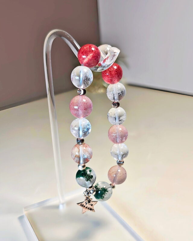 Rooted Glow crystal bracelet hung on a stand, showing the full length of the strand and its star charm.