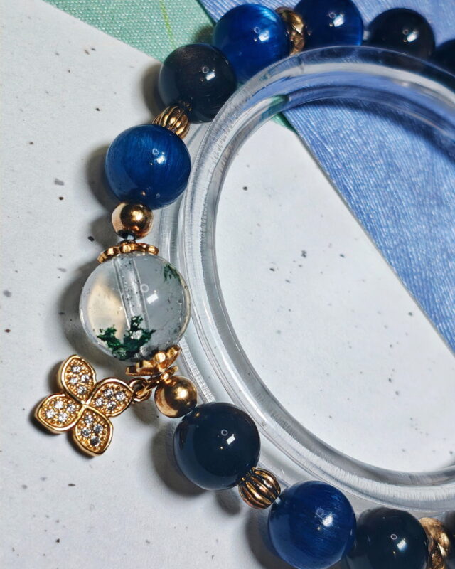 Steady Presence crystal bracelet curved around a clear stand, with its four-leaf clover charm at the centre of the line.