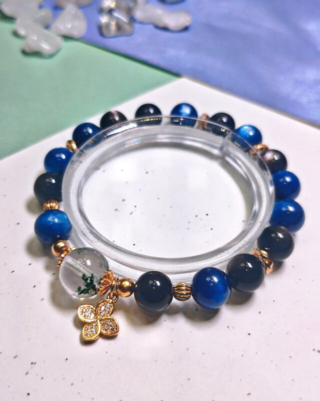 Steady Presence crystal bracelet resting on a clear stand over white and green cards.
