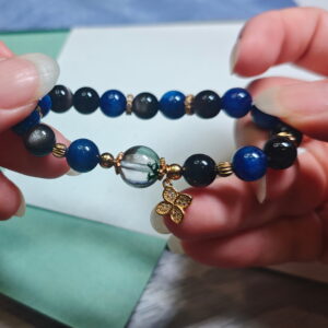 Green phantom quartz bracelet held in two hands, showing the order of the green, blue and silver beads.