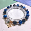 Green phantom quartz bracelet on a clear display stand, with mossy green phantom quartz, deep blue kyanite and silver obsidian beads.
