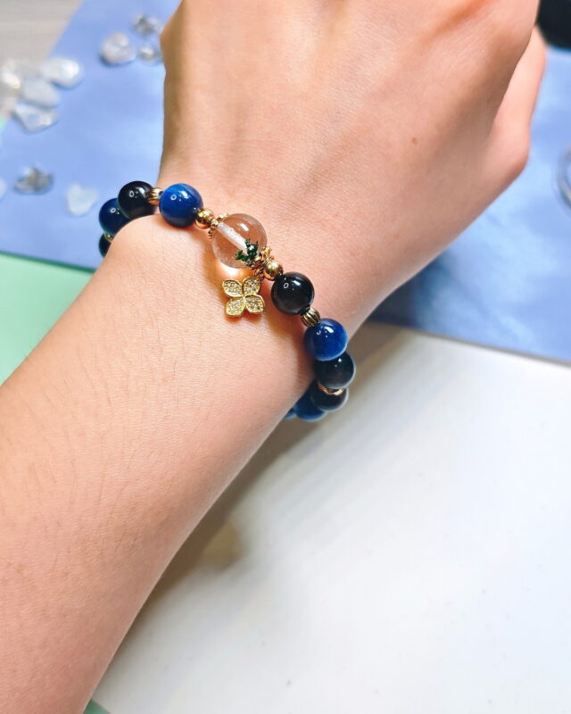 Steady Presence crystal bracelet worn on a wrist, with the four-leaf clover charm sitting at the front.