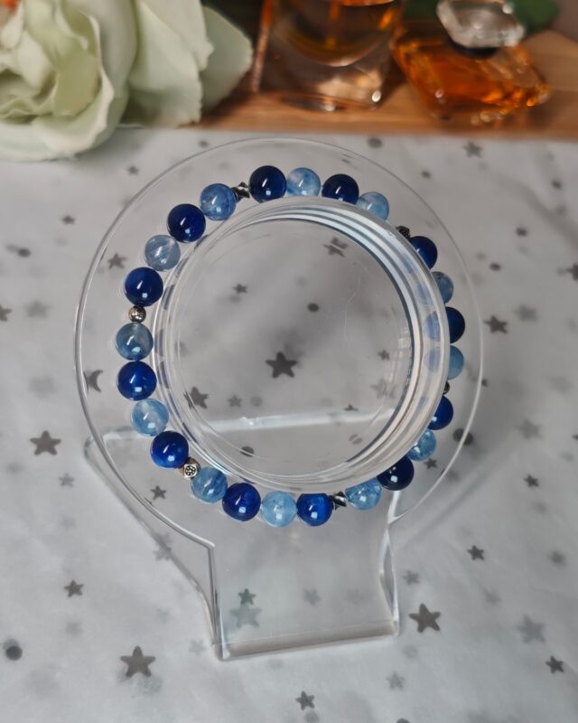 Overview of the still blue crystal bracelet laid around a round stand, showing the alternating blues
