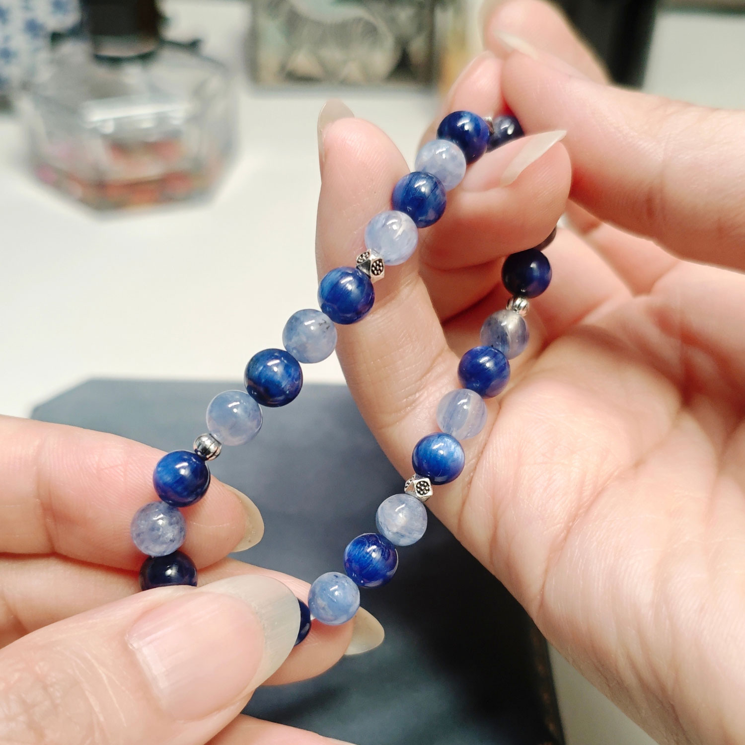Full strand of the still blue crystal bracelet held open between both hands, showing the alternating blues