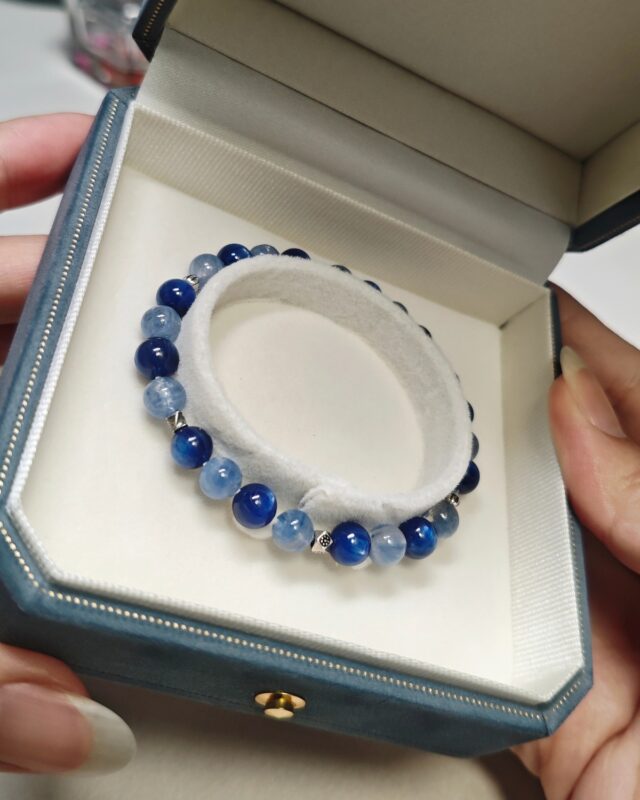 Still blue crystal bracelet resting in an open blue gift box held in two hands