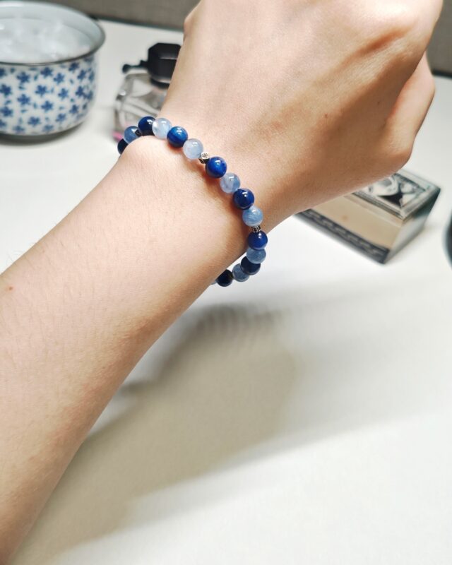 Still blue crystal bracelet worn on the wrist, showing the stretch fit against the skin