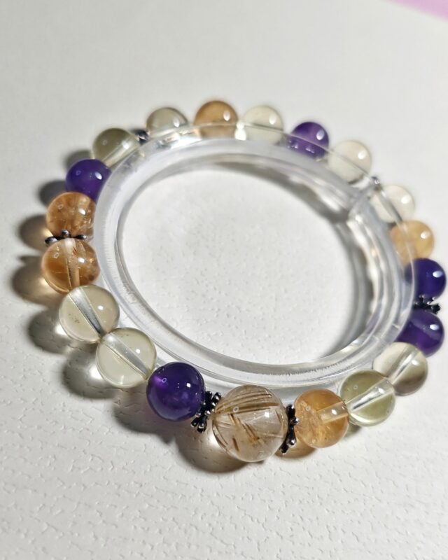 Sunlit hush crystal bracelet laid in a full circle on a clear acrylic disc, amethyst and citrine beads in view