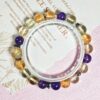 Golden rutilated quartz citrine and amethyst bracelet in a full circle seen from above on printed paper
