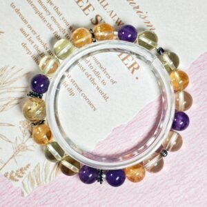 Golden rutilated quartz citrine and amethyst bracelet in a full circle seen from above on printed paper