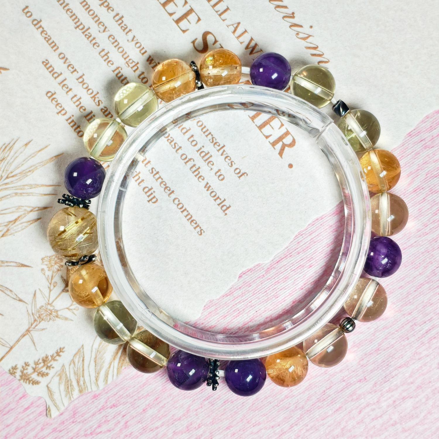 Golden rutilated quartz citrine and amethyst bracelet in a full circle seen from above on printed paper