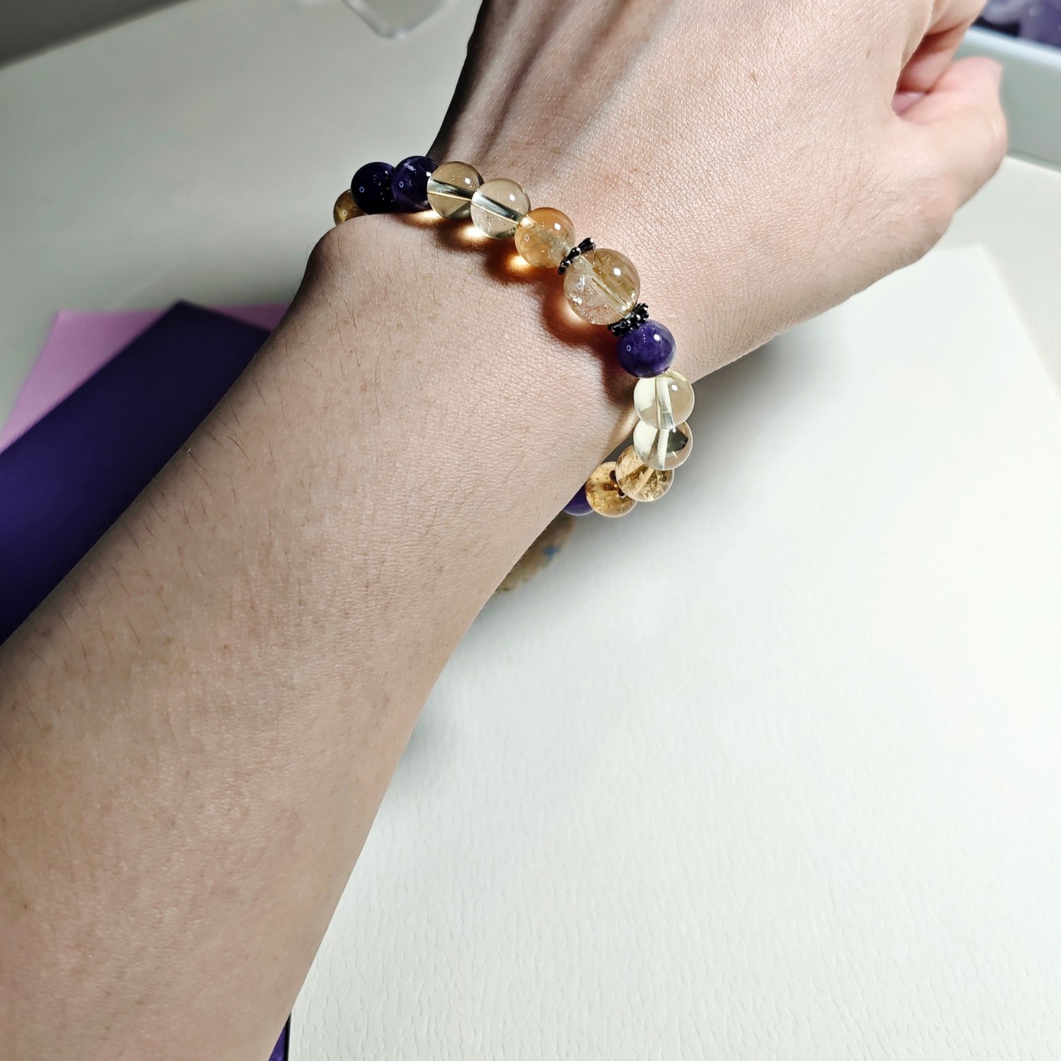 Golden rutilated quartz citrine and amethyst bracelet worn on the wrist in daylight