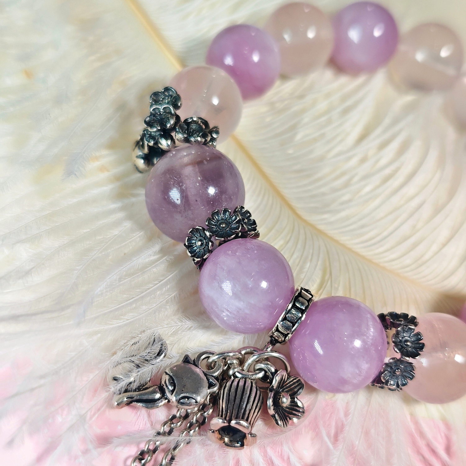 Close view of the purple rutilated quartz bracelet, showing its cat's eye kunzite beads and nine-tailed fox charm.