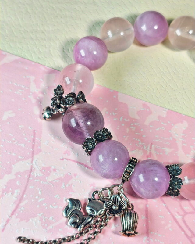Close view of the Tender Charm crystal bracelet, with its sterling silver fox and lily-of-the-valley charm beside the purple beads.