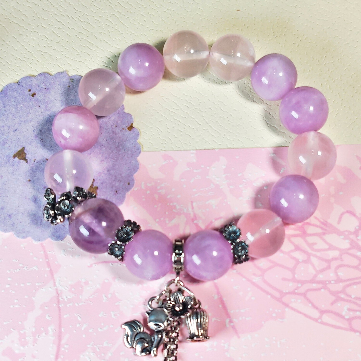 Purple rutilated quartz bracelet shown full circle, with its sterling silver nine-tailed fox charm at the front.