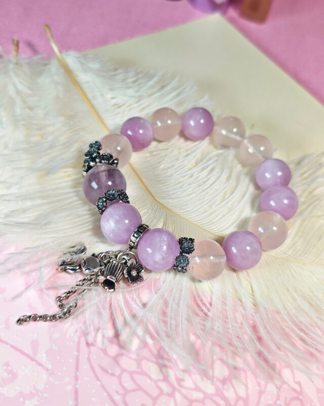 Tender Charm crystal bracelet resting on a soft white feather, with its fox charm in view.