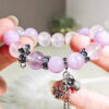Purple rutilated quartz bracelet held in two hands, showing the order of the purple, pink and lavender beads.