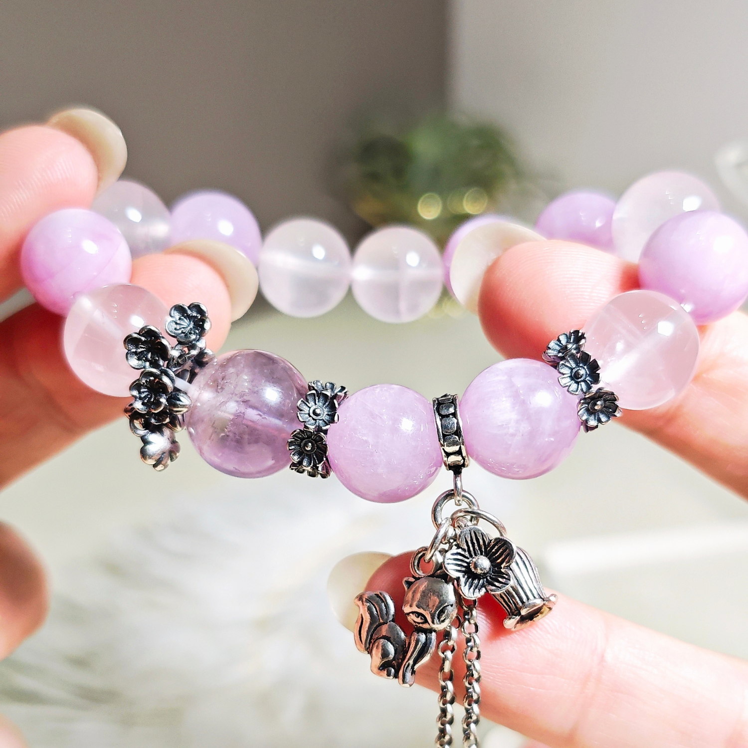 Purple rutilated quartz bracelet held in two hands, showing the order of the purple, pink and lavender beads.