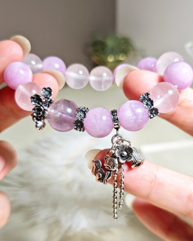 Purple rutilated quartz bracelet held in hand, showing the star rose quartz and cat's eye kunzite beads.