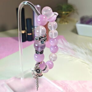 Purple rutilated quartz bracelet hanging on a stand, with its sterling silver fox charm in view.
