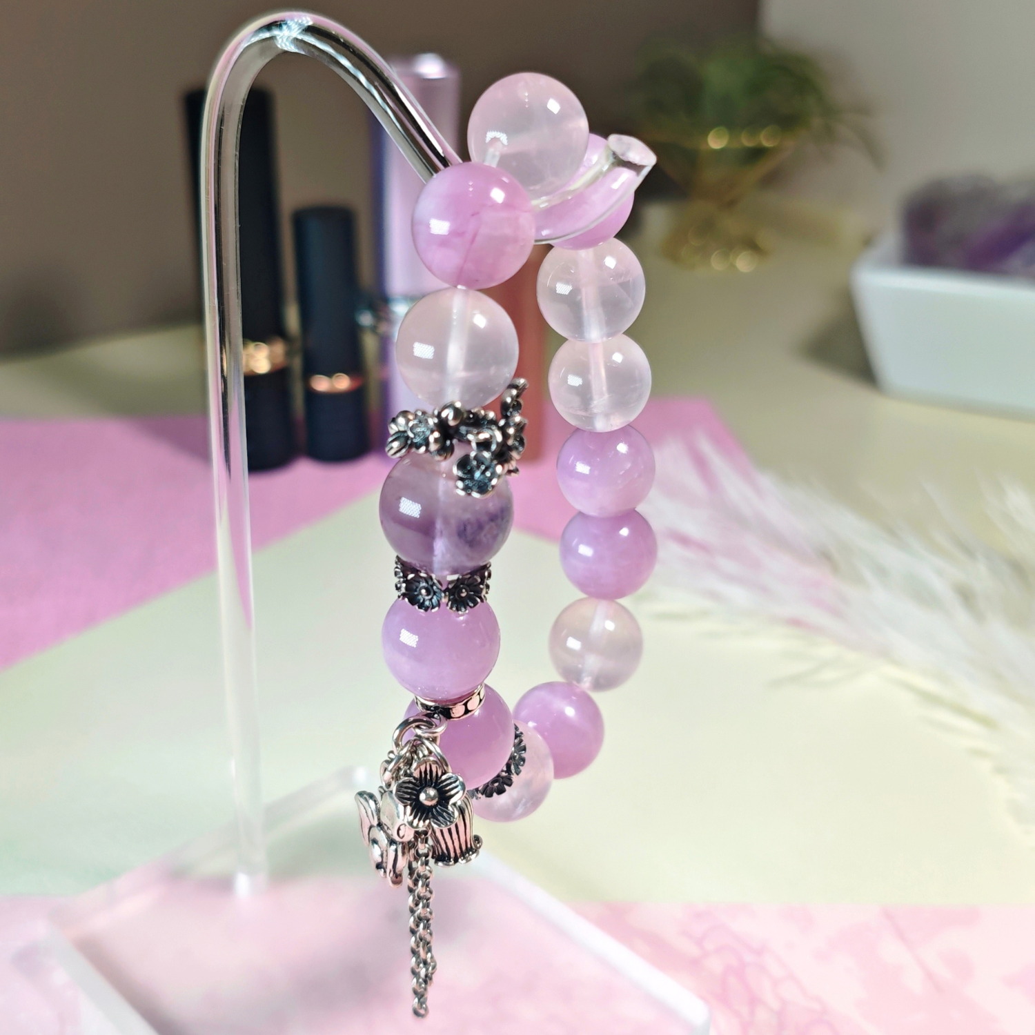 Purple rutilated quartz bracelet hanging on a stand, with its sterling silver fox charm in view.